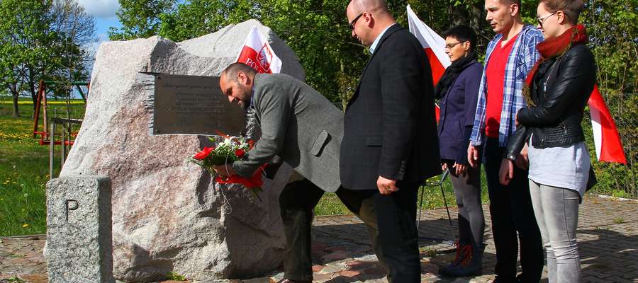 Na zdjęciu Tomasz Węgrzynowski składa kwiaty pod pomnikiem, obok stoi Robert Szaj