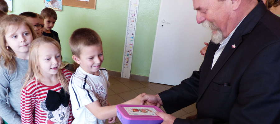 Burmistrz Gołdapi Marek Miros wręcza pudełeczka na drugie śniadanie pierwszoklasistom w Szkole Podstawowej w Grabowie 