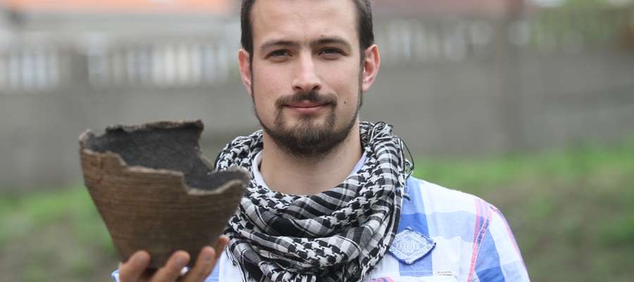 Kacper Martyka, archeolog z Muzeum Warmii i Mazur w Olsztynie z urną z grobu ciałopalnego