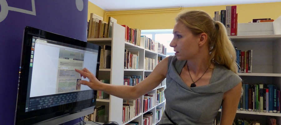 Anna Kucharczyk, kierowniczka filii, prezentuje jedno z nowych stanowisk komputerowych