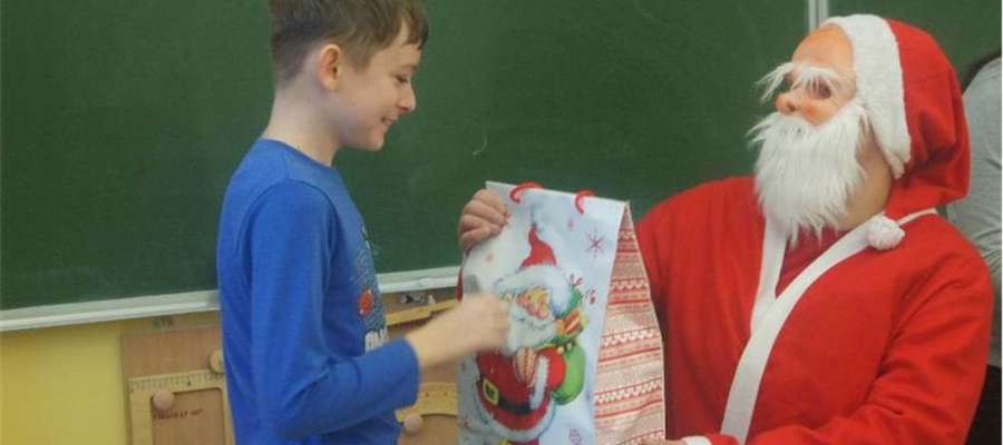 Uczeń szkoły w Gwiździnach odbiera paczkę od Mikołaja 