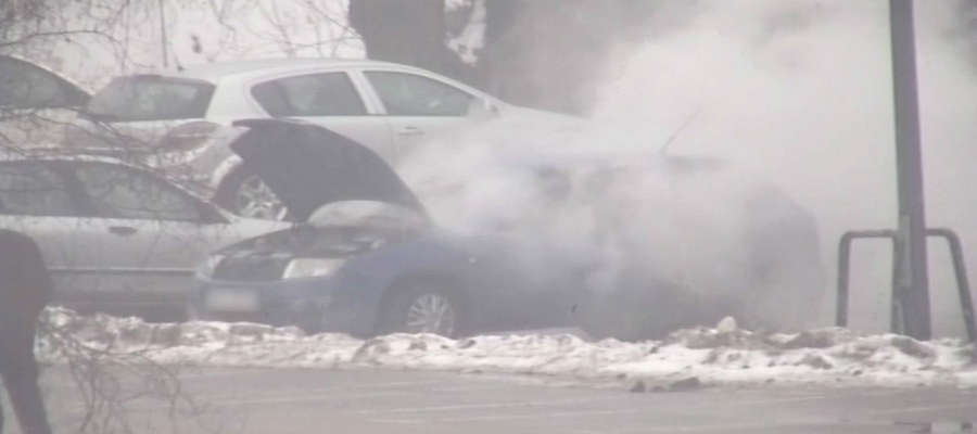 Płonący samochód na parkingu