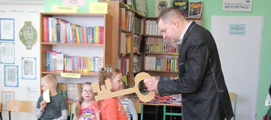 Bibliotekarz – dotykając ramienia każdego z uczniów drewnianym kluczem – uroczyście pasował nowych Czytelników szkolnej biblioteki
