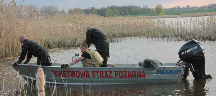 Strażacy wyciągnęli zwłoki mężczyzny owinięte siecią rybacką z wody dawnego jeziora Sajno i przetransportowali na brzeg. 