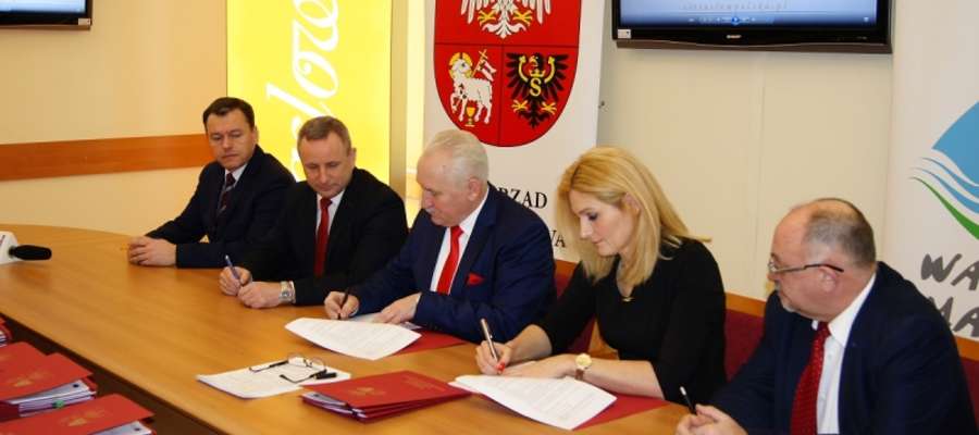 Marszałek województwa warmińsko-mazurskiego Gustaw Marek Brzezin (w środku) podpisuje kolejną pre-umowę