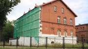 Czerwony mur budynków dawnych koszar znika pod styropianem