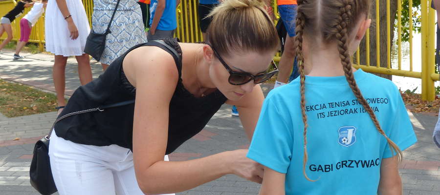 Mama Gabrieli Grzywacz (młoda tenisistka stołowa Jezioraka Iława) przypina jej numer startowy na VIII Iławskim Półmaratonie (2018 r). W Iławie dyscypliny i ich reprezentanci bardzo często przenikają się