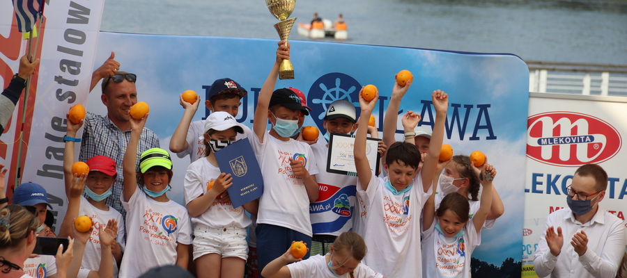 Młodzi żeglarze MOS Iława (wraz z trenerem Michałem Maśkiewiczem) na najwyższym stopniu podium 36. Regat Pomarańczowych, oczywiście z pomarańczami w dłoni