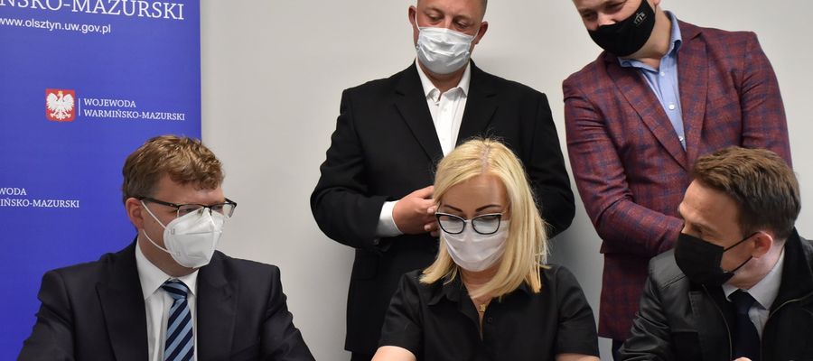 Burmistrz Olecka Karol Sobczak i skarbnik Irena Osmycka podpisują umowę z wojewodą Arturem Chojeckim na dofinansowanie inwestycji drogowych