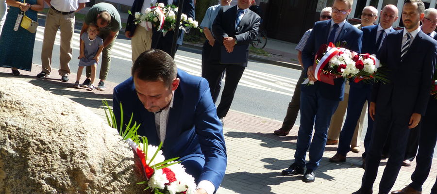 Tomasz Sławiński składa kwiaty przy głazie