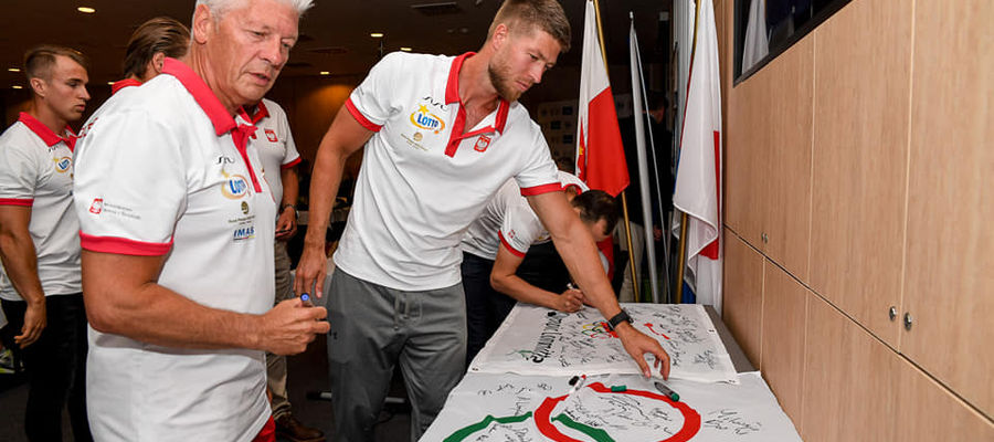 Trener Andrzej Kamiński i jego podopieczny z OKSW (a w "cywilu" syn) Mateusz Kamiński składają pamiątkowe podpisy na olimpijskiej fladze