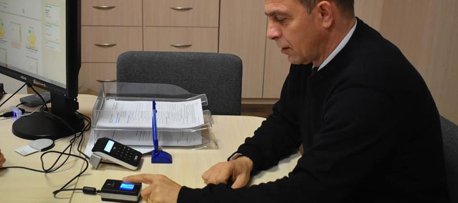 Burmistrz Olecka Karol Sobczak testuje skaner do pobierania odcisków palców 