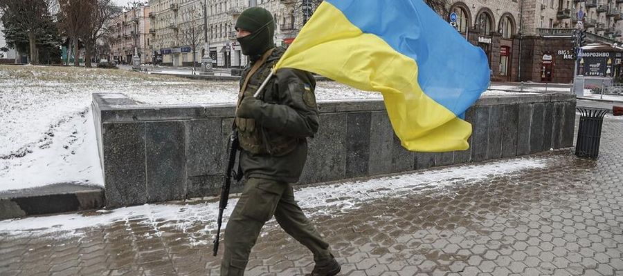 Ukraiński żołnierz niesie przez Kijów flagę państwową 