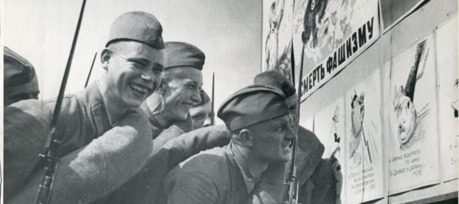 Fot. II wojna światowa. Żołnierze Armii Czerwonej śmieją się z fałszywych plakatów przypominających opuszczenie przez wojsko niemieckie Donbasu i Krymu w 1918 roku. 