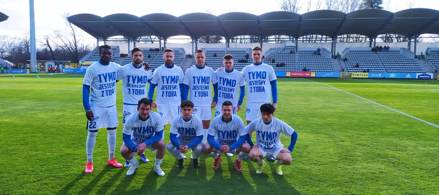 Piłkarze olsztyńskiego klubu wyszli na rozgrzewkę w koszulkach z napisem “Tymo jesteśmy z Tobą”, wspierając w ten sposób poważnie kontuzjowanego kolegę z zespołu, Tomasza Tymosiaka
