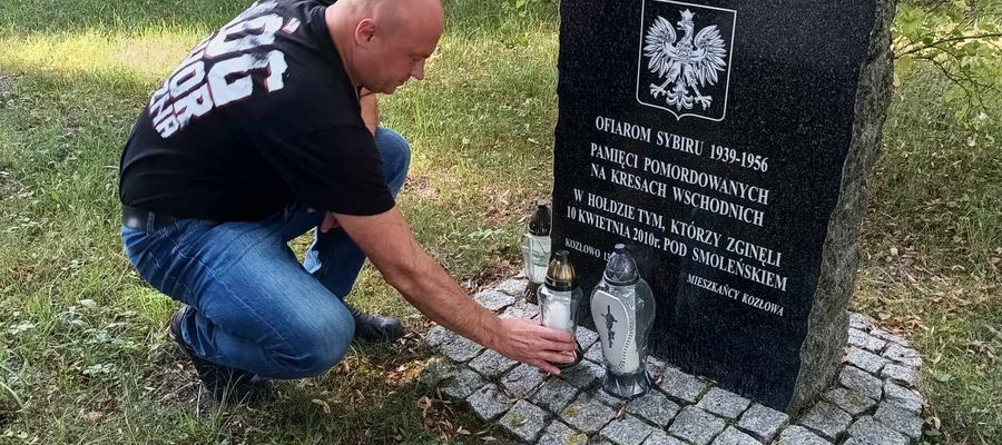 Tomasz Kucmus zapala znicz przy tablicy upamiętniającej m.in. wydarzenia na Wołyniu.