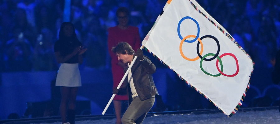 Amerykański aktor Tom Cruise z olimpijską flagą podczas ceremonii zamknięcia igrzysk na Stade de France w podparyskim St. Denis