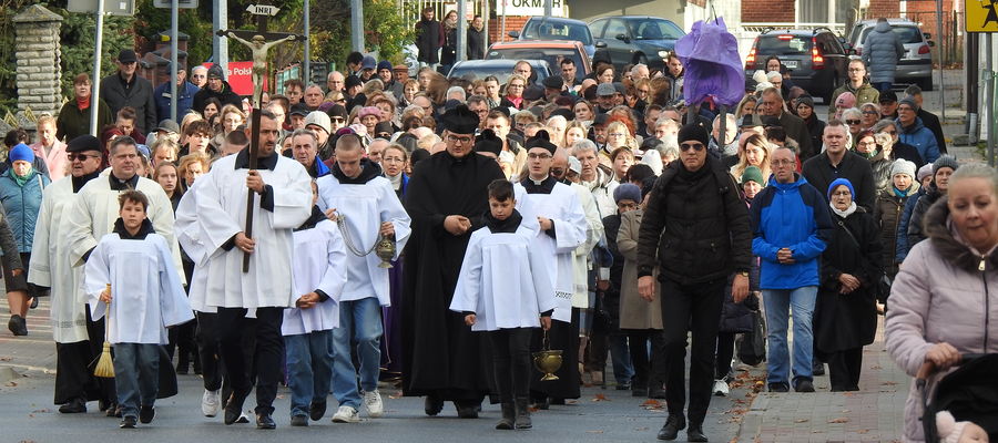 Wierni i duchowni idą na cmentarz parafialny