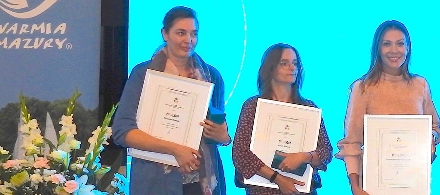 W 2022 laureatką konkursu na pamiątkę regionalną została Natalia Reszka z MCK i Agnieszka Zielińska z nowomiejskiej informacji turystycznej.
Na zdjęciu (w środku) Natalia Reszka podczas wręczenia nagród na Lotnisku w Szymanach