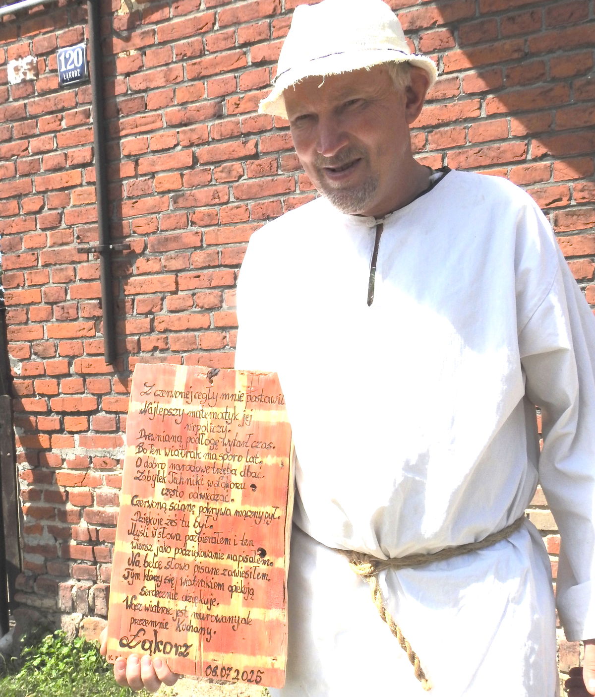 Pasjonat dawnego młynarstwa prezentuje tablicę, którą zawiesił w łąkorskim wiatraku